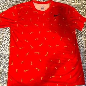 Nike Dri-Fit red tee with bold black swoosh logo and all-over gold swoosh